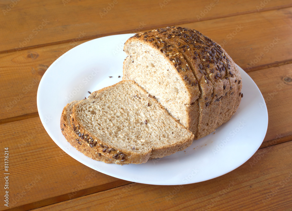 Sliced grain bread on white plate on brown wooden surface Sliced grain bread on white plate on brown wooden surface
