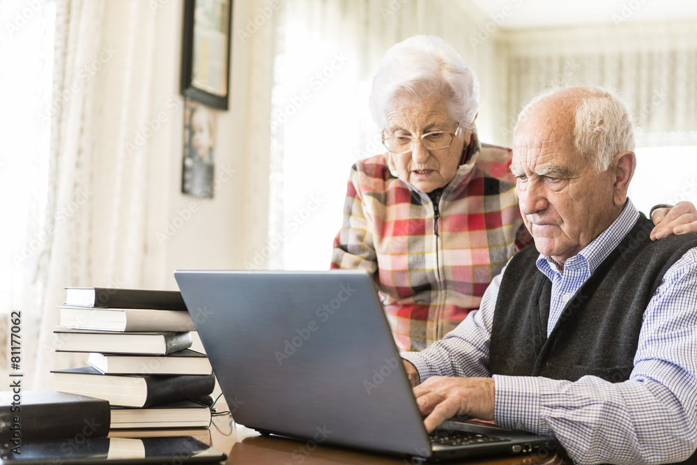 Senior couple working with Laptop and books at home Senior couple working with Laptop and books at home