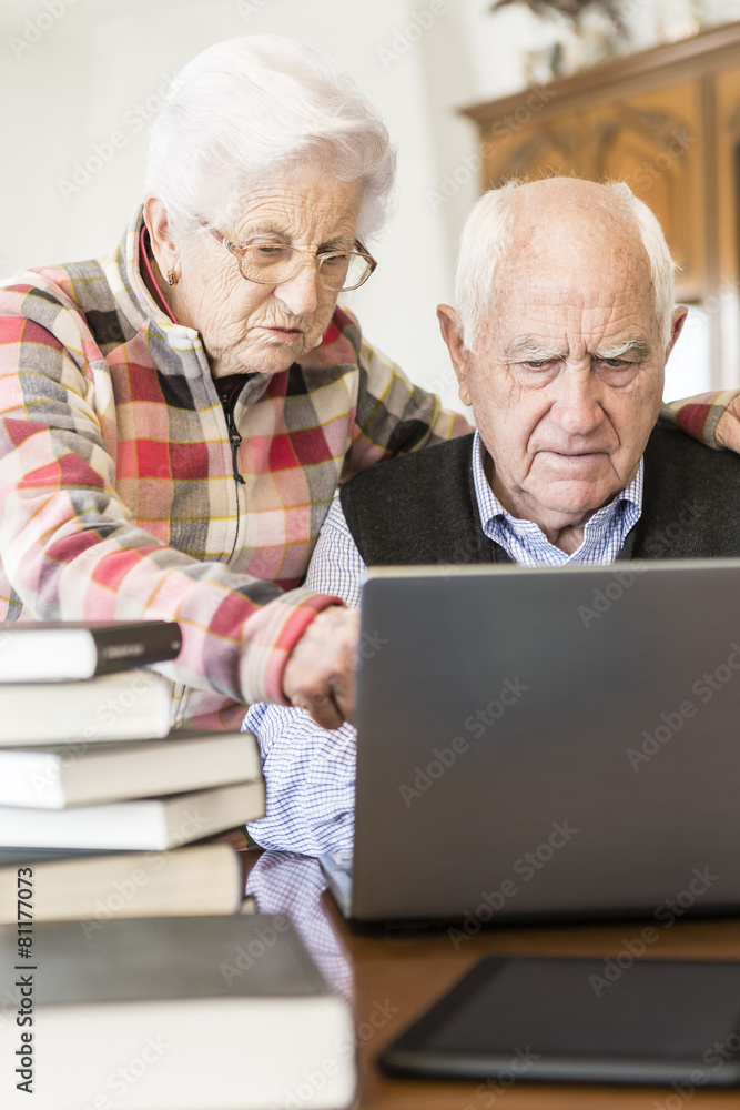 Senior couple working with Laptop and books at home Senior couple working with Laptop and books at home