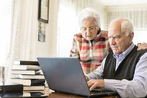 Senior couple working with Laptop and books at home