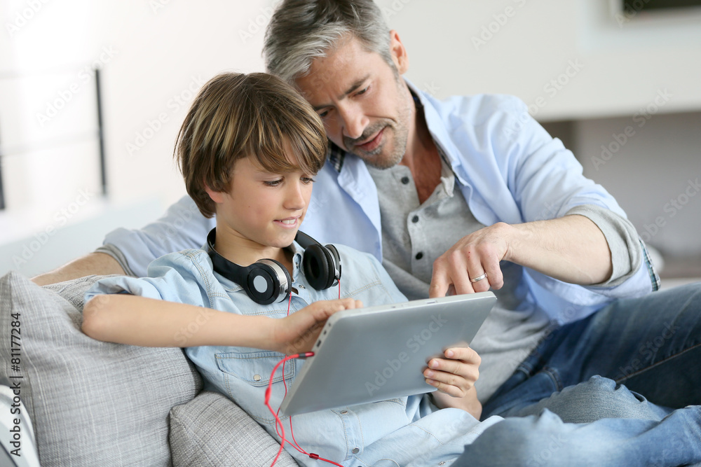 Father watching kid playing with tablet Father watching kid playing with tablet