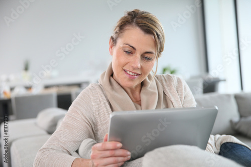 Free Download Mature woman sitting in sofa and websurfing with tablet - GFXLoad