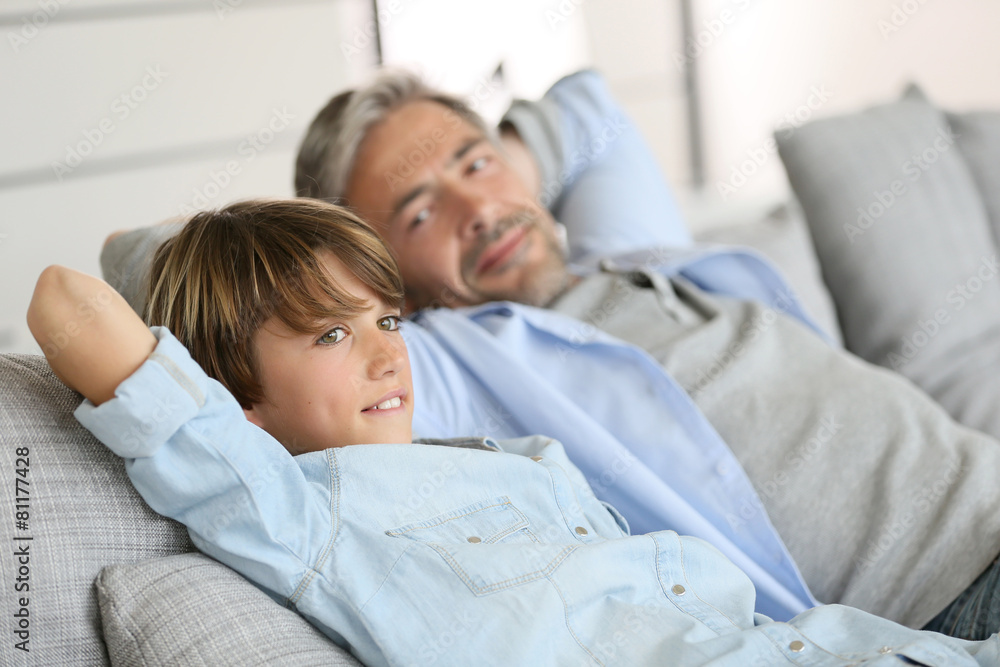 Father and son relaxing in sofa a thome Father and son relaxing in sofa a thome