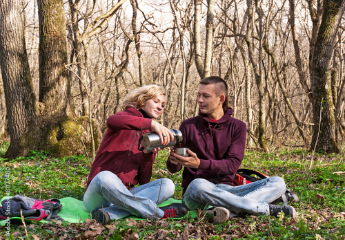 Happy couple drinking tea in the forest