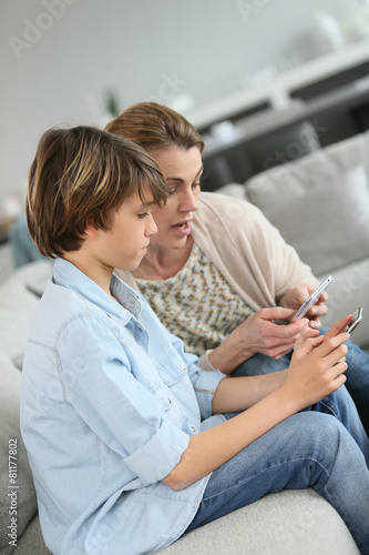 Mother and teenage boy playing with smartphone