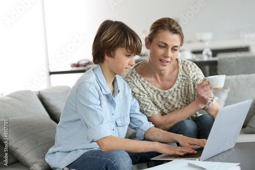 Mother looking after son doing homework on laptop