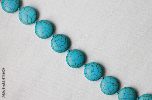Line of turquoise stone beads bijouterie on white background