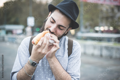 young handsome hipster gay modern man eating hot dog photo