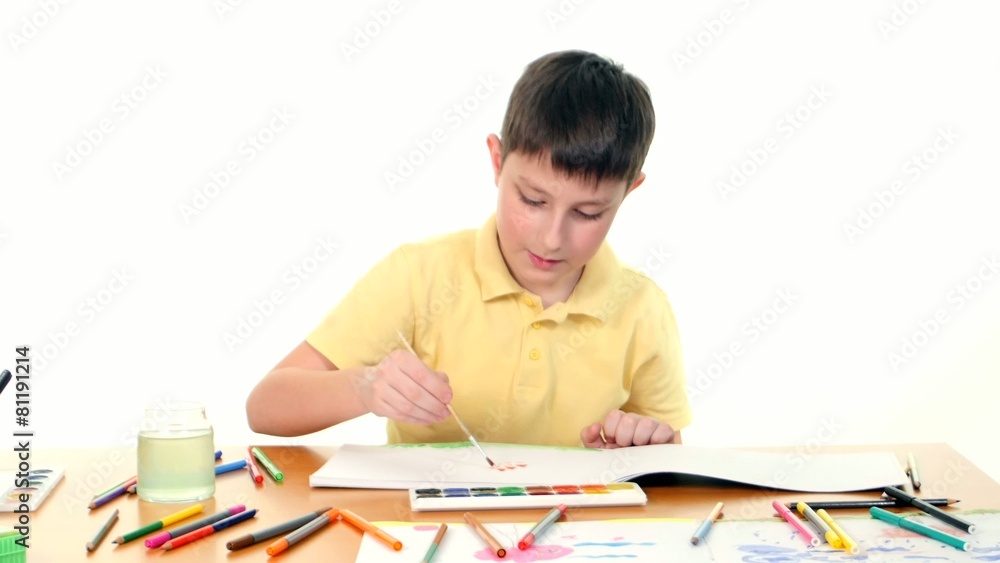 Dark-haired little boy paints colors on white background Dark-haired little boy paints colors on white background