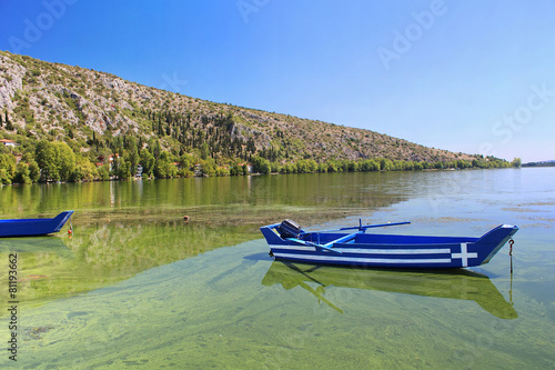 Blue traditional old wooden fishing boat with Greece flag