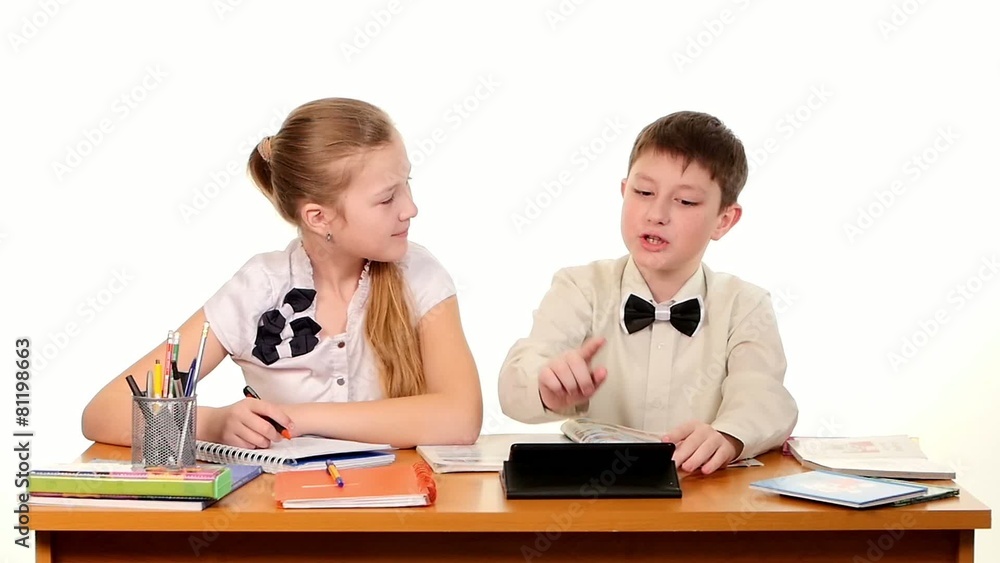 School children sitting by the table, doing homework and School children sitting by the table, doing homework and
