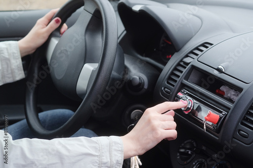 Woman adjusting radio volume in the car.