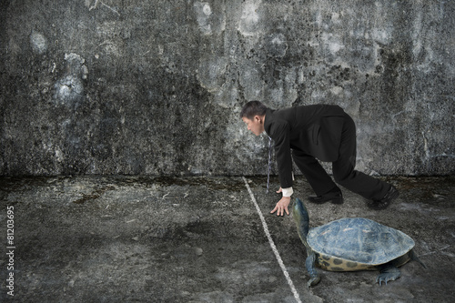 Businessman and turtle are ready to race on concrete floor