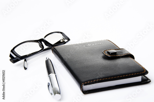 Black glasses, notebook and ballpoint pen