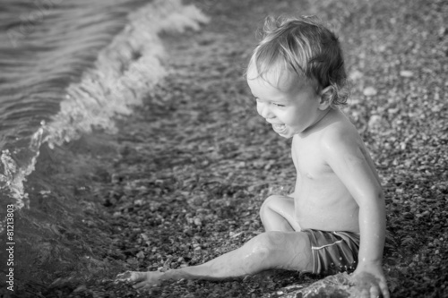Happy toddler boy playing on the sea