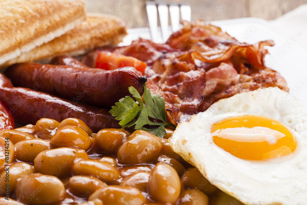 Full english breakfast with bacon, sausage, fried egg, baked bea Full english breakfast with bacon, sausage, fried egg, baked bea