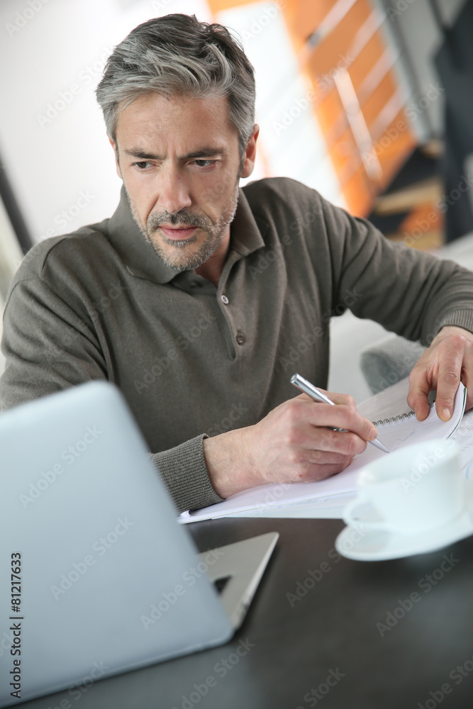 Mature man calculating budget on laptop