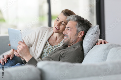 Mature couple using digital tablet relaxing in sofa © goodluz
