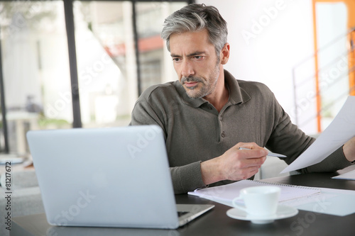 Mature man calculating budget on laptop photo