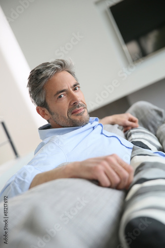 Mature man in living-room, relaxing in sofa
