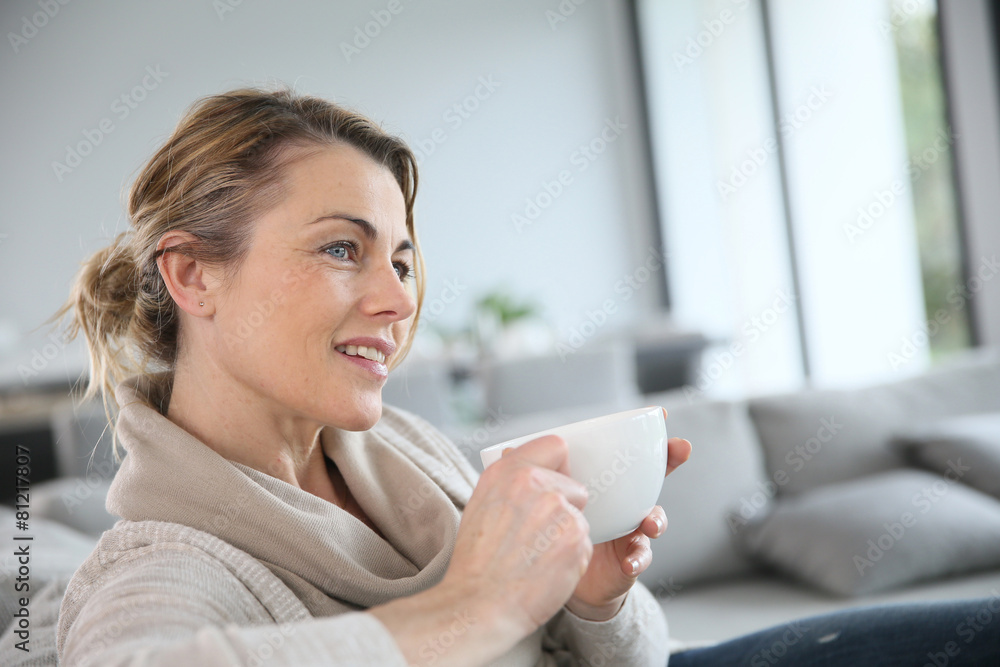 Fototapeta premium Mature woman in sofa drinking hot coffee