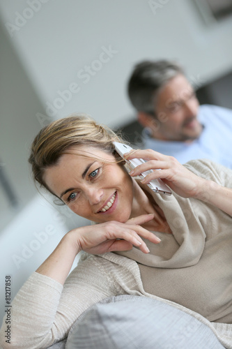 Mature woman talking on smartphone, husband using tablet © goodluz