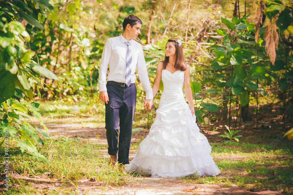bride and groom walk hand in hand through jungle