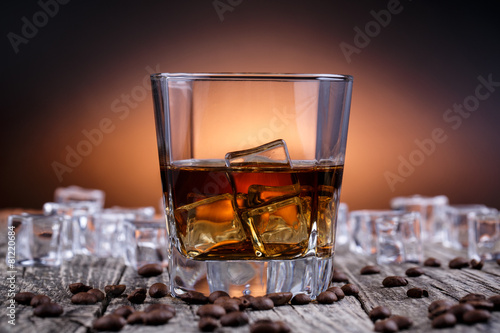 Glass of whiskey with ice and coffee beans.