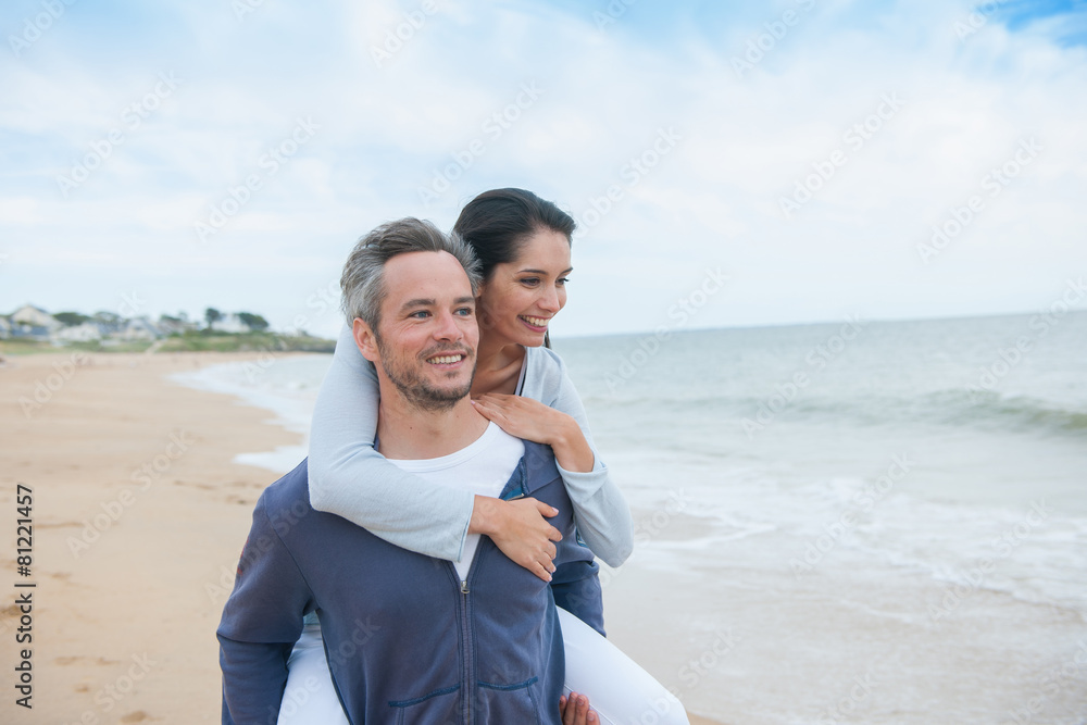 A beautiful couple is posing holding eachother at the beach