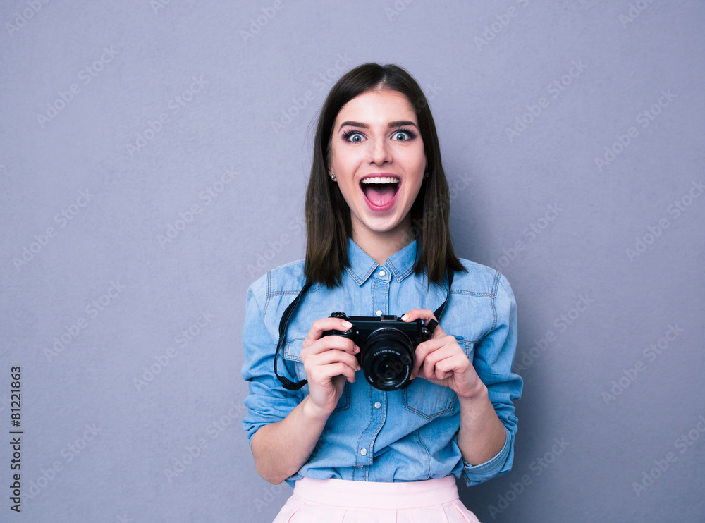 Amazed young pretty woman holding camera
