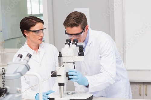 Scientists looking attentively in microscope