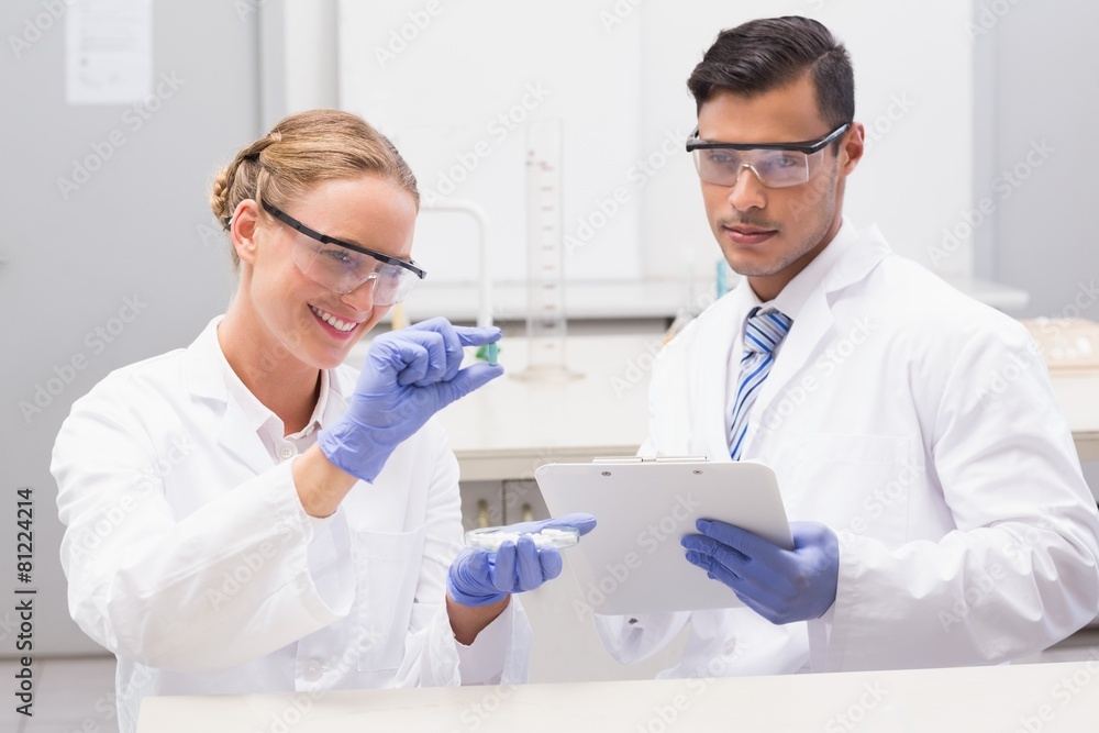 Scientists looking at petri dish and taking notes Scientists looking at petri dish and taking notes