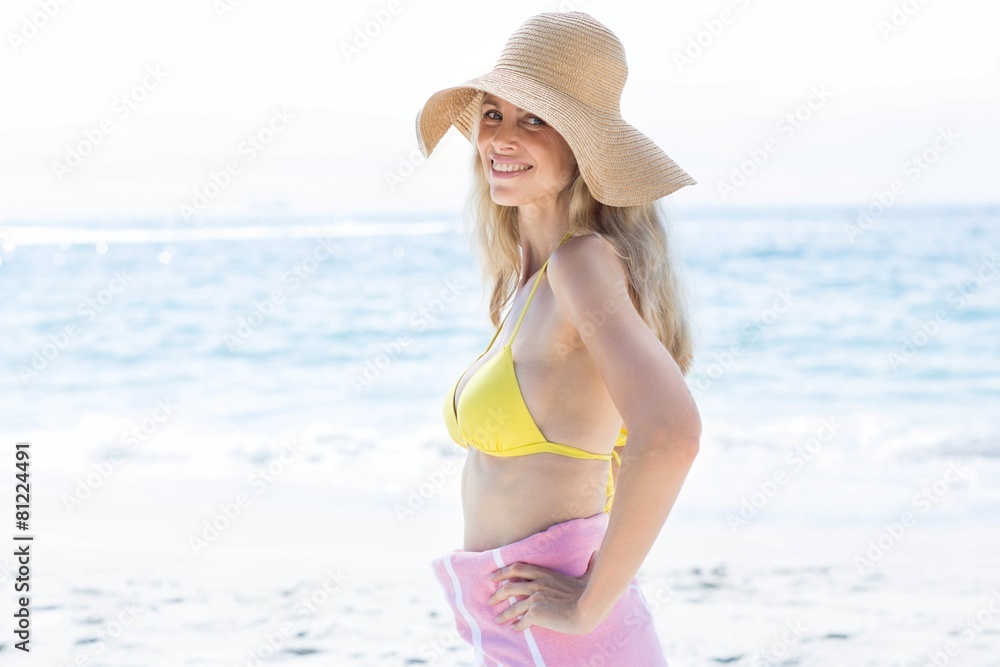 Smiling blonde standing by the sea and looking at camera