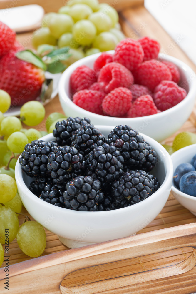 fresh berries and green grapes on a wooden tray, vertical fresh berries and green grapes on a wooden tray, vertical