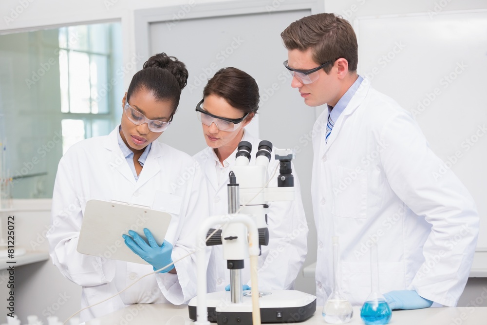 Scientists working with microscope and taking notes Scientists working with microscope and taking notes