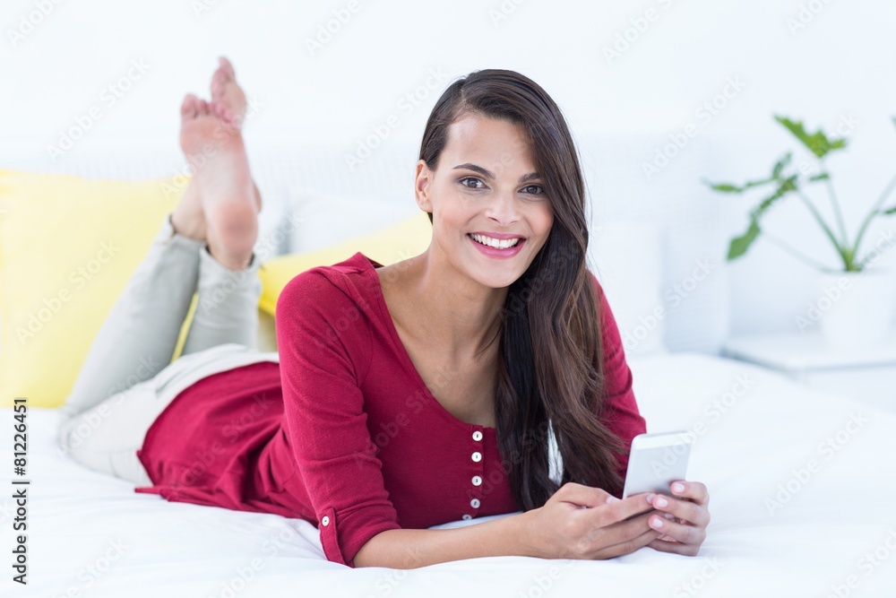Beautiful woman using her smartphone lying on bed Beautiful woman using her smartphone lying on bed