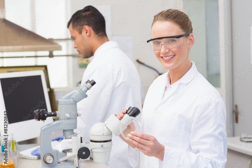 Scientist examining petri dish smiling at camera Scientist examining petri dish smiling at camera