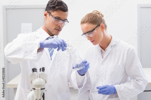 Focused scientists examining beaker