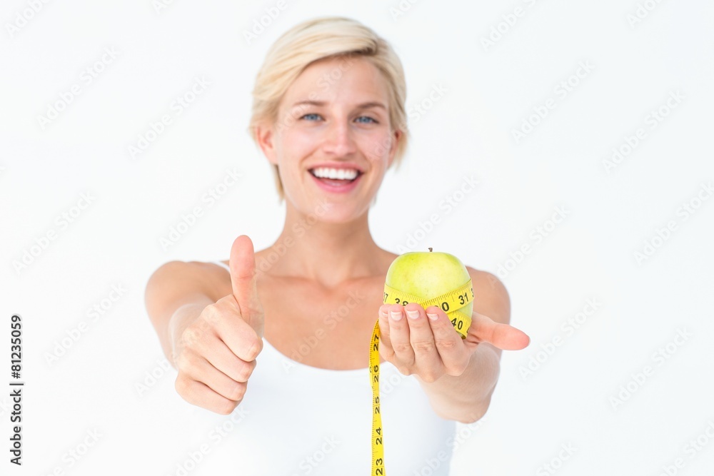 Happy woman holding an apple with thumbs up Happy woman holding an apple with thumbs up