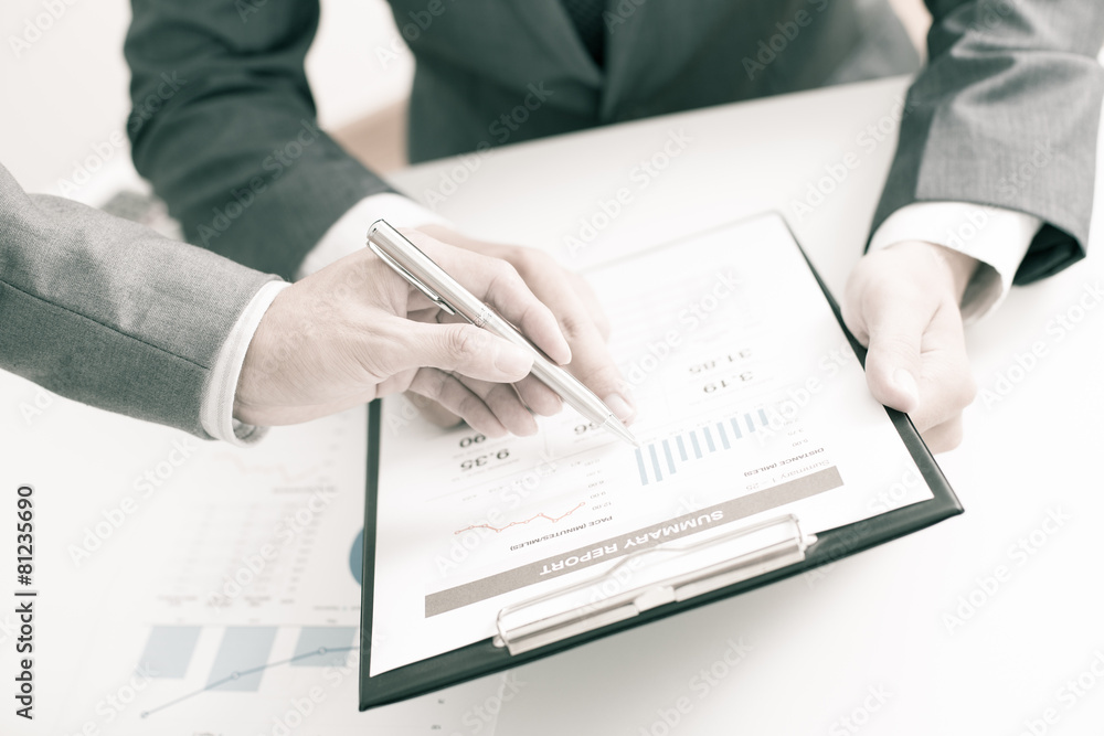 Two businessmen looking at report and having a discussion in off Two businessmen looking at report and having a discussion in off