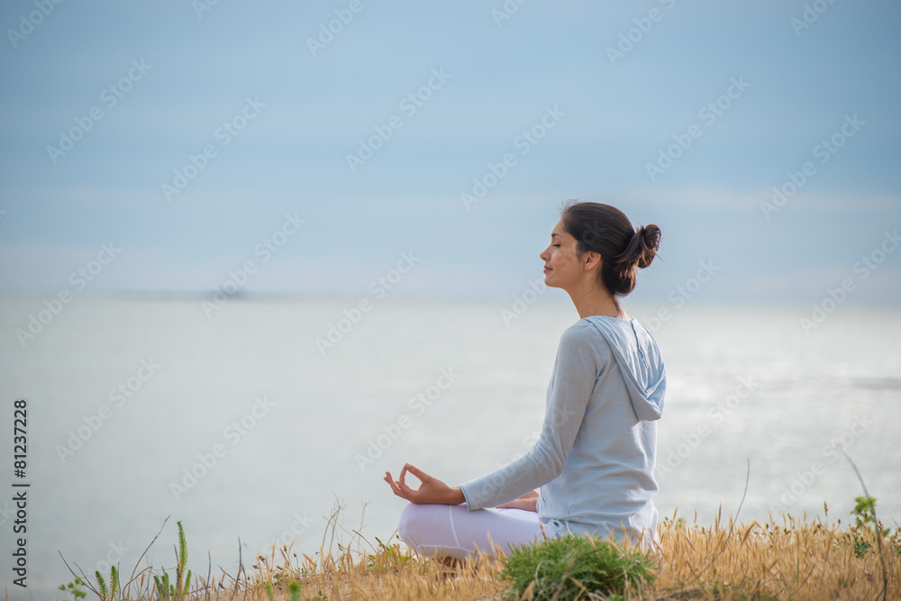 Woman meditating face to the ocean
