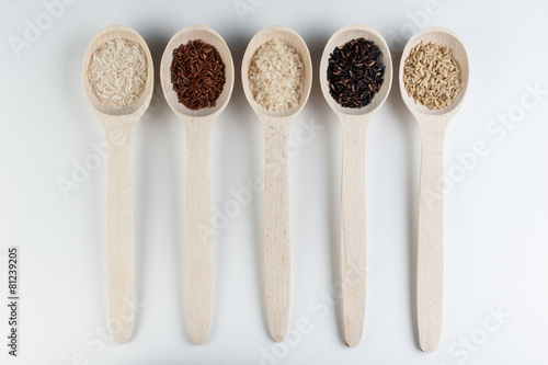 Different kinds of rice in spoons isolated on white background