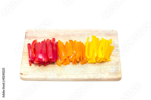 Red orange yellow peppers sliced on a cutting board