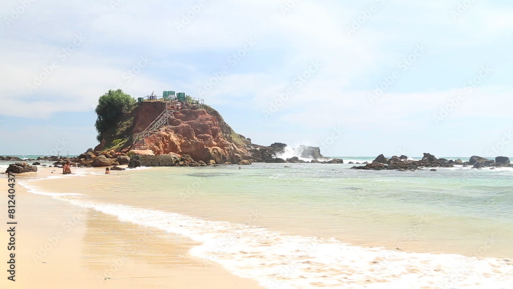 WELIGAMA, SRI LANKA - MARCH 7, 2014: Timelapse of people enjoying at sandy beach in front of the viewpoint on a big rock where you can see both sides of Weligama bay. WELIGAMA, SRI LANKA - MARCH 7, 2014: Timelapse of people enjoying at sandy beach in front of the viewpoint on a big rock where you can see both sides of Weligama bay.