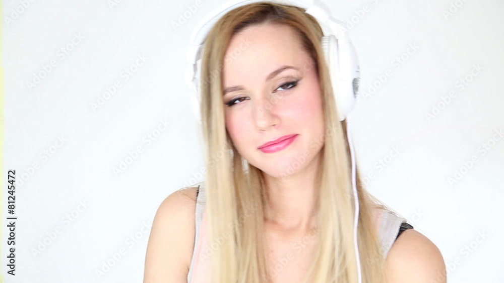 Beautiful young blond woman dancing with white headphones in white bright background Beautiful young blond woman dancing with white headphones in white bright background