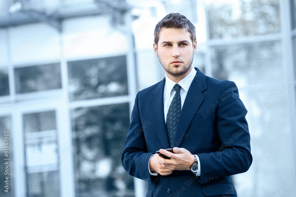 Attractive young businessman using a cell phone. Attractive young businessman using a cell phone.
