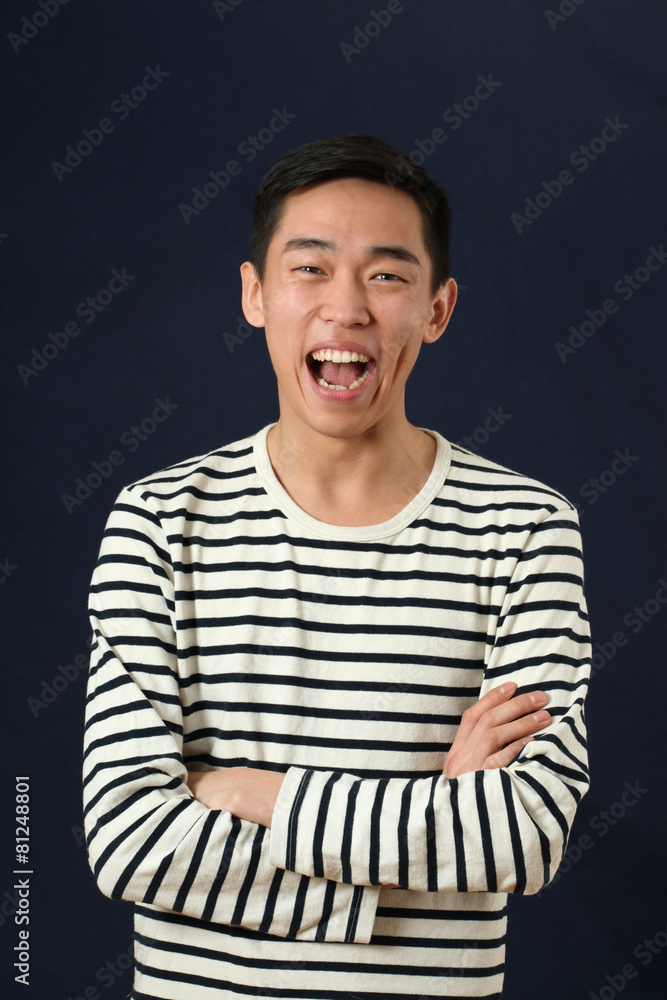 Laughing young Asian man with crossed hands looking at camera