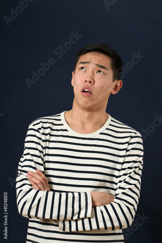 Disappointed young Asian man with crossed hands looking up