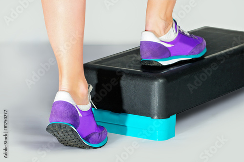 Female feet in violet sneakers on fitness step. photo