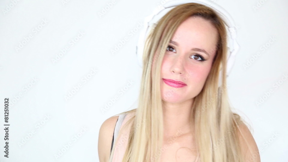 Beautiful young blond woman dancing with white headphones in white bright background Beautiful young blond woman dancing with white headphones in white bright background